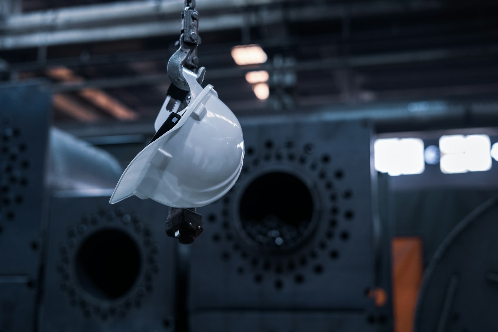 Casque de chantier suspendu devant une machine dans un atelier industriel
